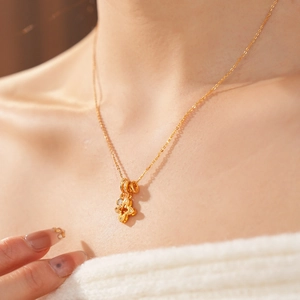 Close-up of gold-plated clover pendant necklace with sparkling cubic zirconia on model
