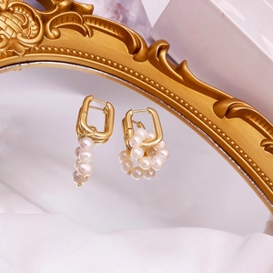 Detailed close-up of baroque freshwater pearls on gold square hoop earrings on mirror