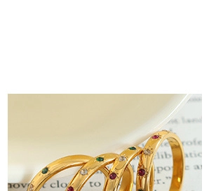 Close-up of four gold-plated stacking rings with colorful zircon starburst settings