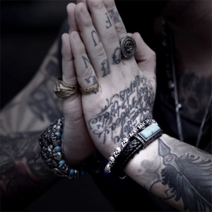 Detail showing layers of punk skull bracelets and metal rings with blue stone accents