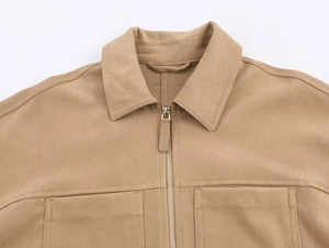 Gros plan sur une veste marron texturée avec col à revers, zip métallique et poches