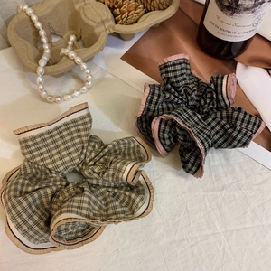 Retro plaid oversized scrunchies in khaki and dark brown colors on a textured cloth