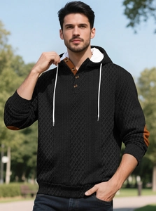 Détail d'un sweat à capuche noir avec tissu texturé et fermeture à boutons au col