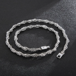 Gros plan d'un collier chaîne torsadée de 6 mm en acier inoxydable argenté sur fond noir