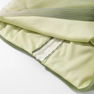 Detailed close-up of light green gradient pleated fabric with concealed zipper