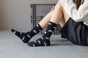 Detail of black cotton socks featuring blue cloud patterns and ribbed cuffs on model