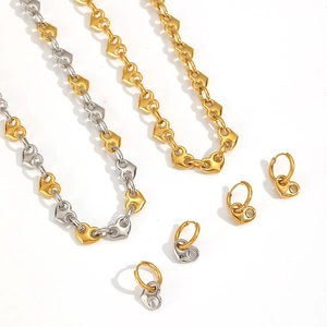 Macro detail of 18k gold and silver heart-shaped link necklaces and earrings set