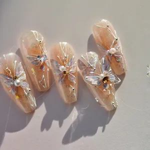 Detailed view of pink gradient nail stickers with 3D butterfly wings and pearls