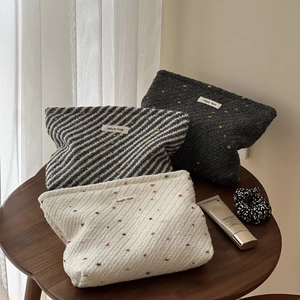 Three minimalist woven cosmetic bags in polka dot and twill patterns with zipper closure