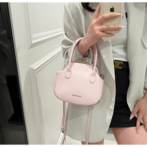 Detail of pink vintage doctor bag with metallic clasp and round handle on white blazer