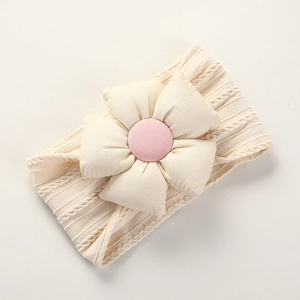 Detailed close-up of beige knitted baby headband with fabric flower and pink center