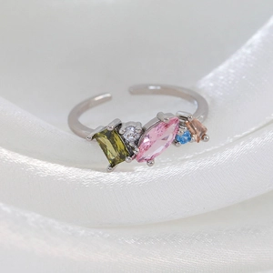 Detailed macro of adjustable silver ring with colorful zircon stones on white silk fabric