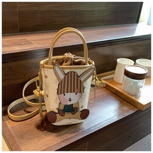Detail of a beige and brown leather bucket bag with a cartoon rabbit and drawstring