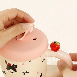 Detail of opening pink silicone lid on cute ceramic cat mug with apple ornament