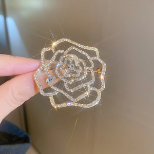 Detailed close-up of a vintage hollow rose brooch with sparkling crystals and gold finish