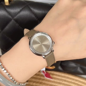 Detail of luxury women's watch with rhinestone bezel and green leather strap on wrist