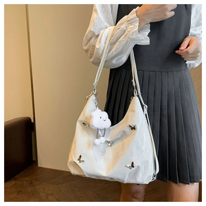 Detail view of white tote bag with metallic butterflies and plush cloud charm