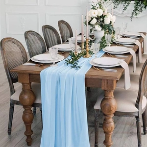 Detail of light blue chiffon table runner draped elegantly on a vintage wooden dining table