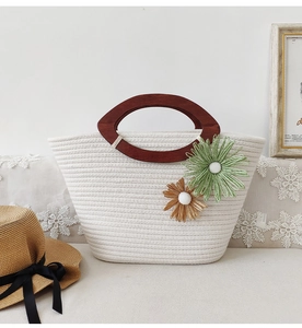 Detail of white cotton woven tote with wooden handles and floral charms in a cozy setting