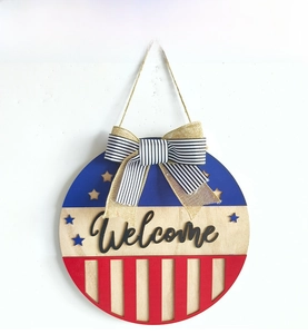 Detail view of wooden Independence Day wreath sign with Welcome text and striped bow