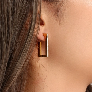 Detail showing 18K gold plated rectangular earrings with white crystals on a model