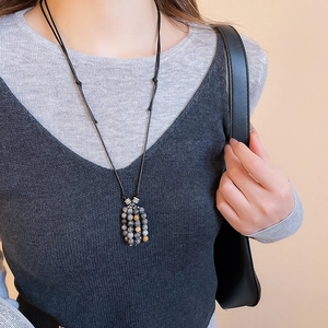Close-up of vintage stone bead fringe pendant on a black adjustable rope chain