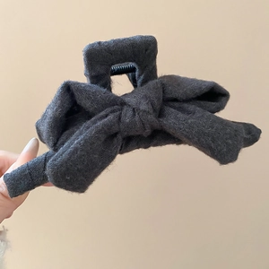 Detailed macro view of black tweed fabric bow hair claw clip showing textile texture