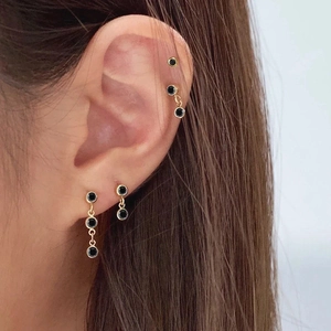 Close-up of elegant gold stud earrings with round black zircon stones on model