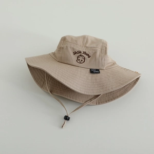 Detail of beige children's bucket sun hat with adjustable strap and cute embroidery.