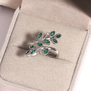 Détail macro d'une bague feuille en argent avec gemmes vert émeraude en écrin de velours