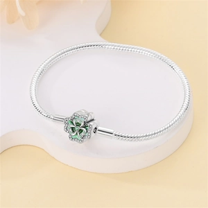 Silver beaded bracelet with clover clasp featuring green enamel and pavé stones on white stand
