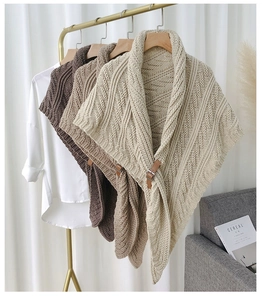 Detail view of knitted shawls with leather buckles in cream, beige, and dark brown colors