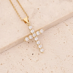 Detailed shot of gold-plated cross pendant with micro-paved zircons on a stone background