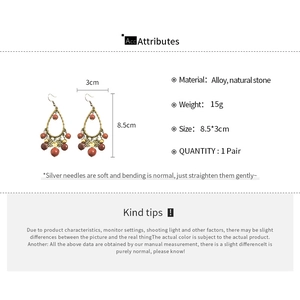 Detail view of ethnic teardrop earrings with red stone beads and alloy hollow frames