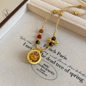 Ethnic gold pearl pendant necklace with rotating mask and agate stone on woven rope