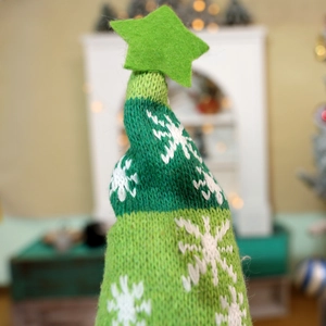 Close-up of green knitted Christmas hat with white snowflake patterns and felt star