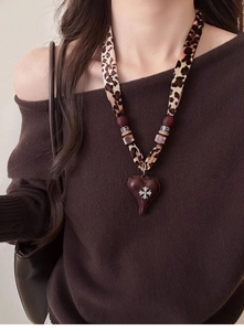 Detail of leopard print fabric strap necklace with heart pendant and cross motif