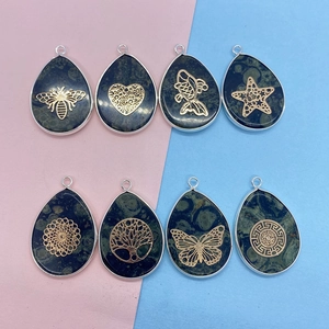Detailed view of teardrop stone pendants with gold metal tree of life and bee overlays