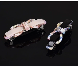 Detail view of colorful acetic acid bow hair clips with rhinestones on black reflective surface