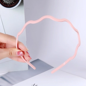 Close-up of pink wavy plastic headband showing anti-slip inner teeth and smooth finish