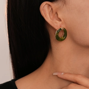 Close-up of elegant olive green resin hoop earrings with gold trim worn by a model