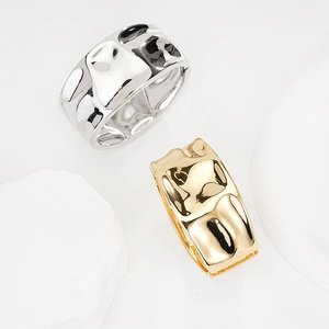 Detailed view of wide irregular hammered metal cuffs in gold and silver finishes
