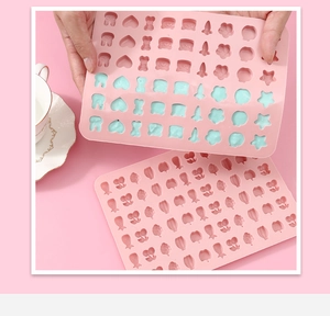 Detail of hand using a pink silicone mold with animal and fruit shapes for DIY candies