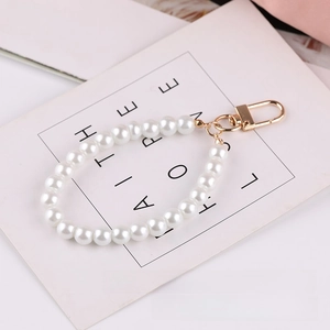 Detail of white glass pearl keychain with a secure golden metal clasp on a card