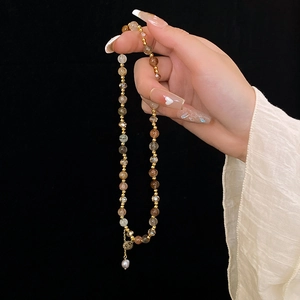 Detail of multi-layer crystal beaded bracelet with gold relief tag and pearl drop