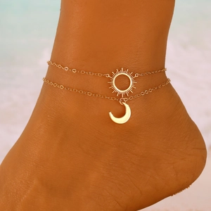 Double-layered gold anklet with sun and moon pendants worn on the beach for women