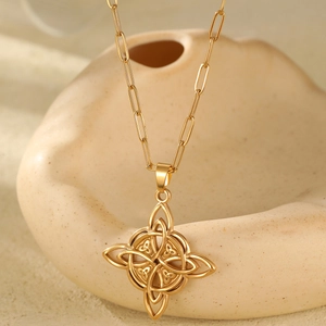 Detail of a gold Celtic knot sun pendant hanging on a trendy paperclip chain necklace