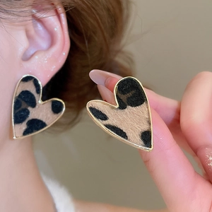 Close-up of heart-shaped leopard print earrings with gold metal frame and plush texture