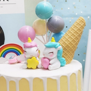 Macro detail of cartoon unicorn cake toppers with rainbow and balloon decorations