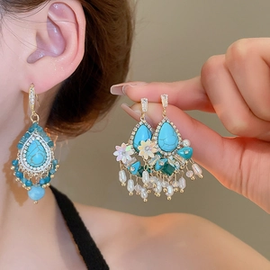 Detail of luxury teardrop turquoise tassel earrings with pearls and crystals on ear lobe